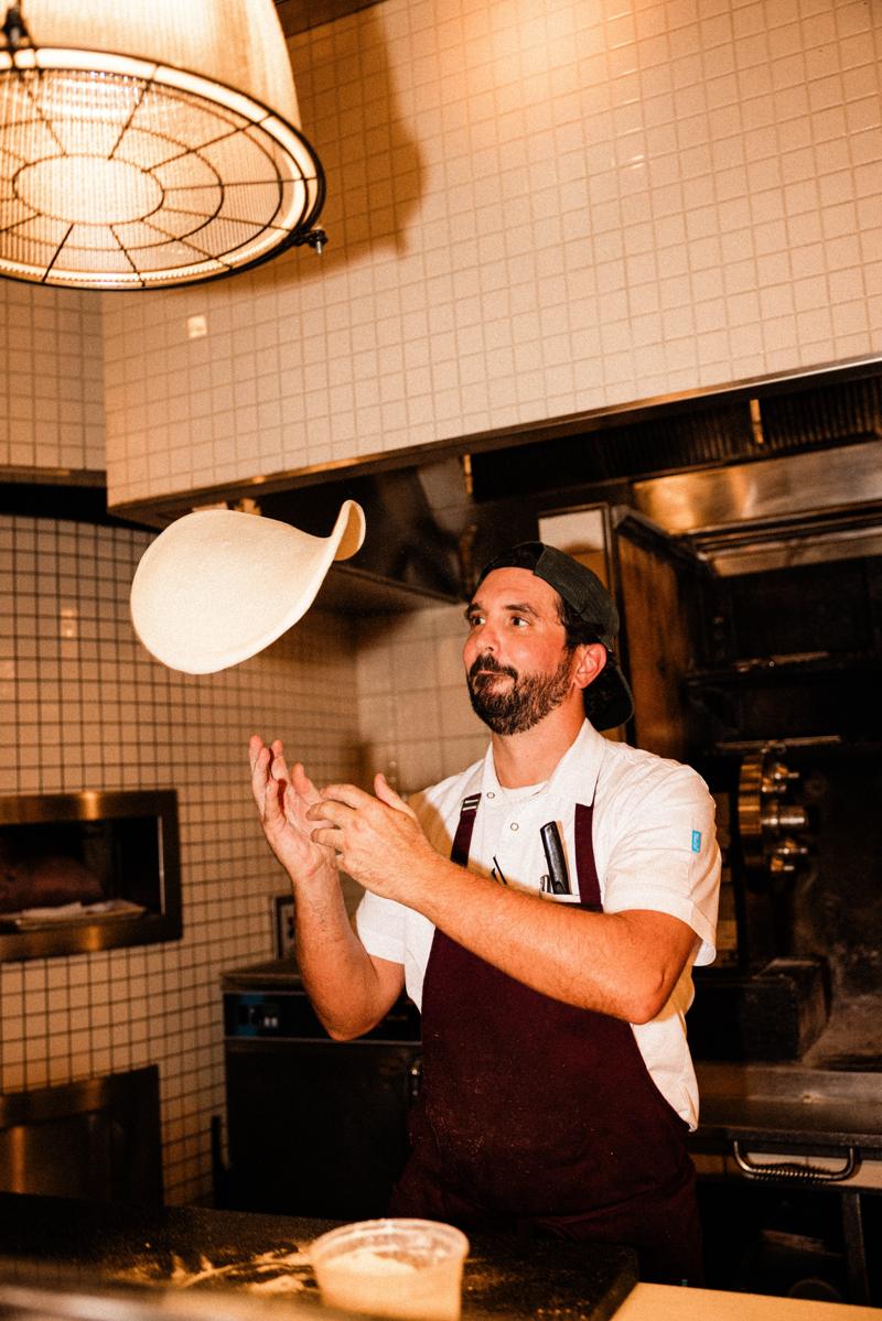 Pizza dough tossed in the air in the open kitchen